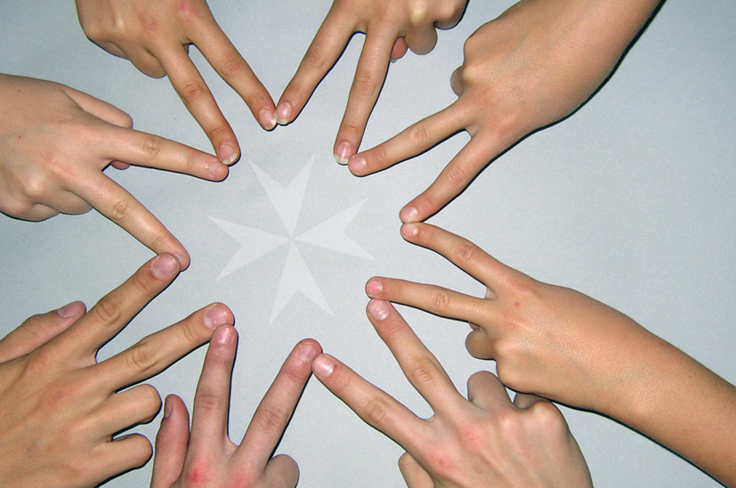 Acht Hände bilden mit ihren Fingern das Malteser-Kreuz