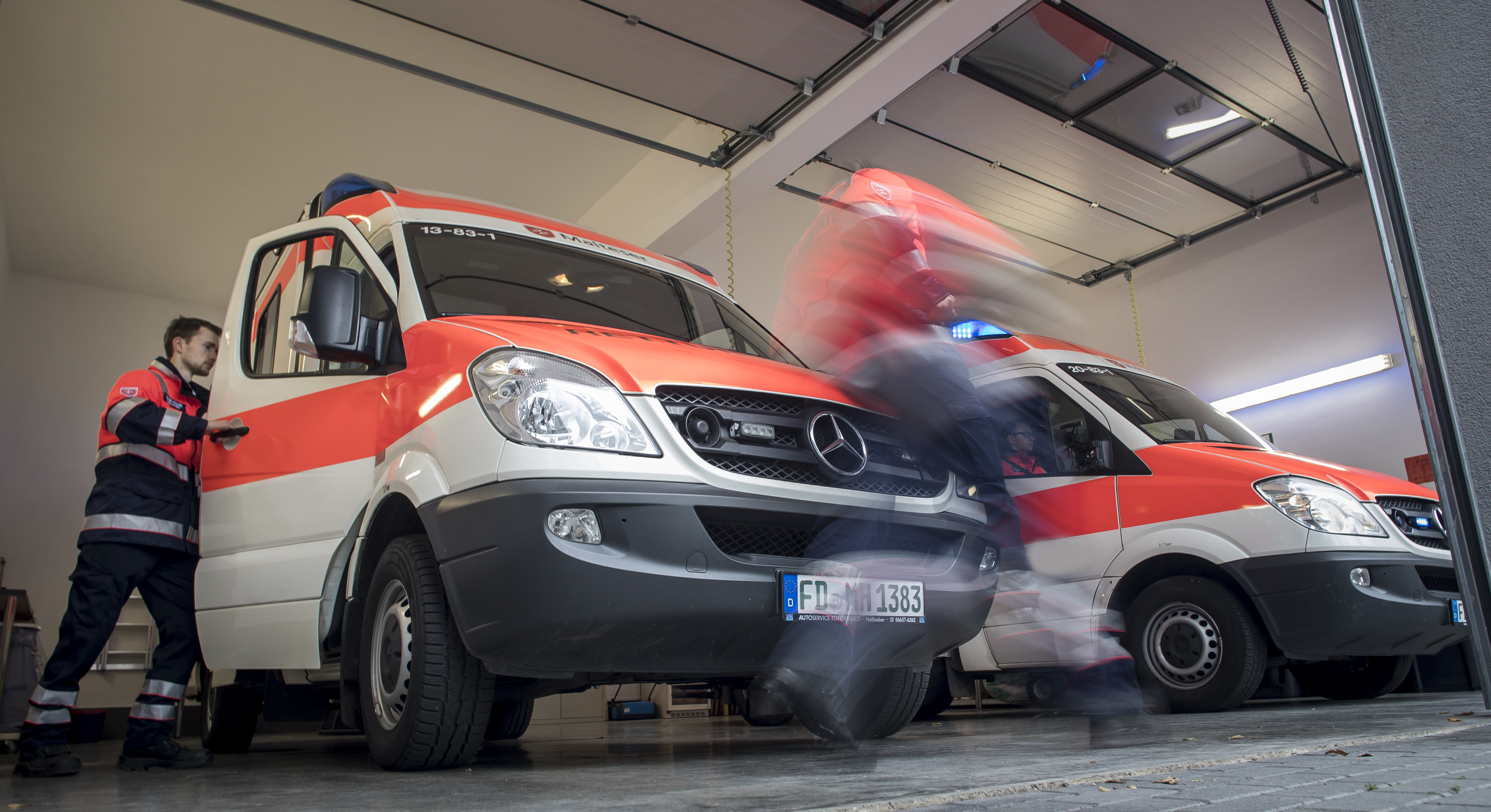 Zwei Mitarbeiter der Malteser sprinten in den Rettungswagen, um zum Einsatz zu fahren.