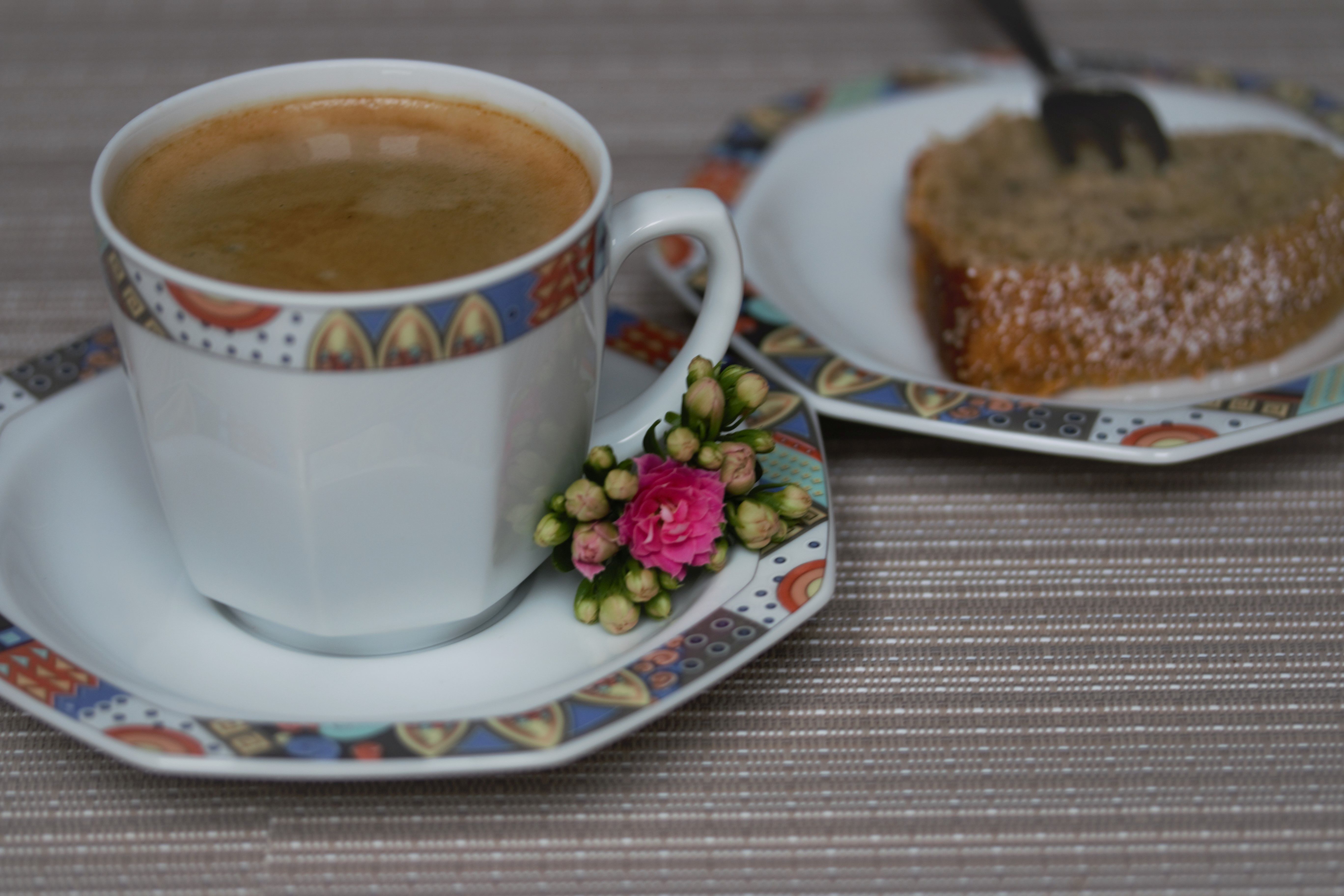 Auf einem Tisch steht eine Tasse Kaffee und ein Teller mit einem Stück Kuchen.