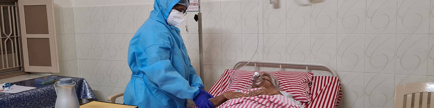 Arzt in Quarantäne-Kleidung hält Arm eines Patienten 