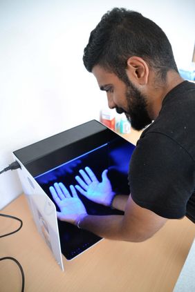 Ein Teilnehmer prüft mittels eines Fluoreszenz-Tests die korrekte Händedesinfektion.