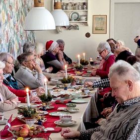 Senioren sitzen an einer weihnachtlich geschmückten Kaffeetafel.