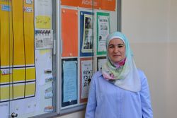 Maha Hussein steht in einem Schulflur neben einer Informationstafel.